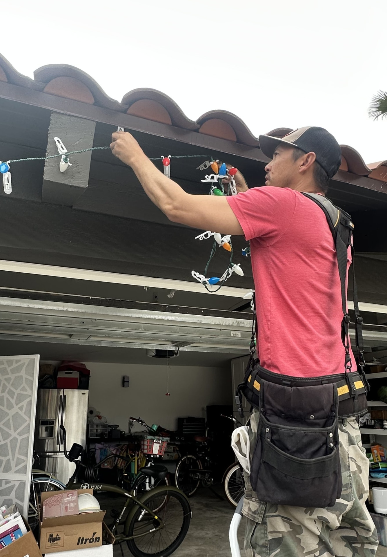 Installer clipping C9 bulbs onto a clay tile roofline during a daytime installation